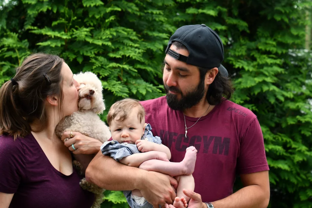 man in red crew neck t-shirt carrying baby in white and brown fur coat